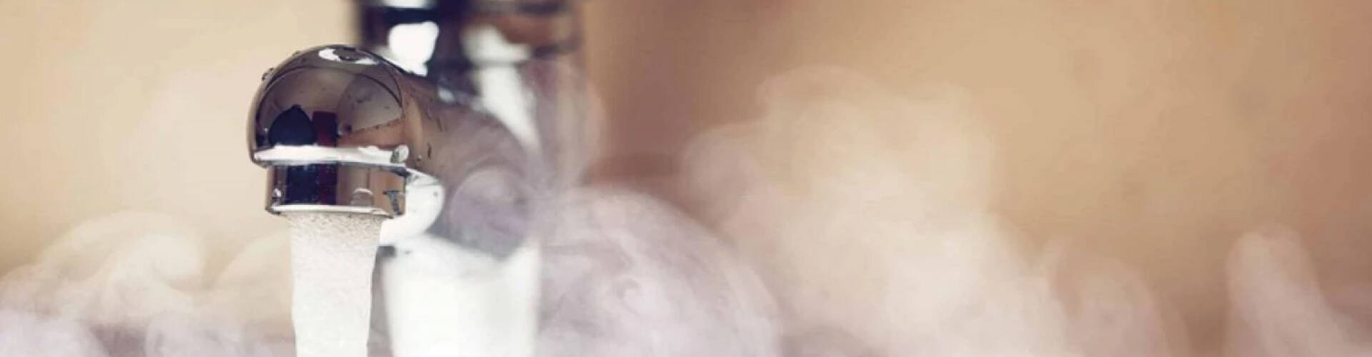 Torneira liberando &aacute;gua quente, com vapor ao redor.