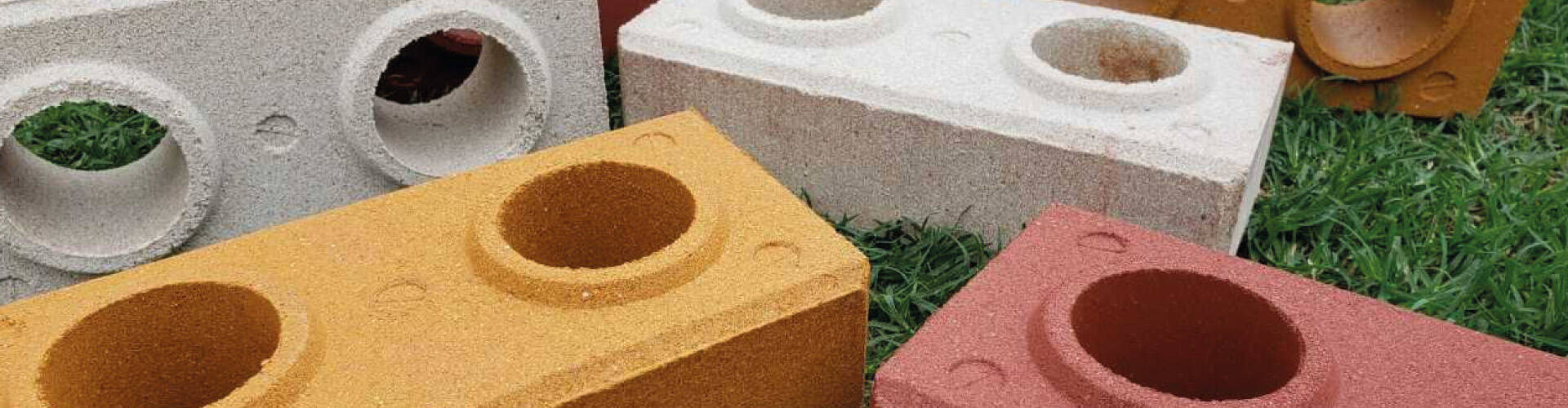 Tijolos ecol&oacute;gicos de v&aacute;rias as cores numa grama verde.